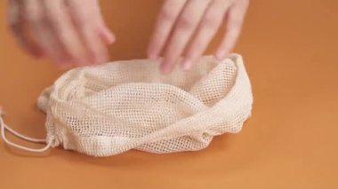 Kadının ellerinin biberleri alıp pamuk kesekağıdına koyduğu yakın plan.