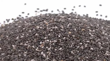 Bir avuç dolusu pişmemiş chia tohumu dönüyor. Egzotik tahıllar, sağlıklı gıda konsepti. İzole edilmiş, beyaz arka planda. Seçici odak atışı