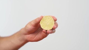 Erkek eli, sulu taze limon sıkıyor. Sağlıklı vejetaryen yemekleri. İzole edilmiş, beyaz arkaplanda