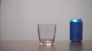 Adam mavi soda kutusundan bardağa şeker döküyor. Şeker tatlandırılmış içecekler. İzole edilmiş, beyaz arkaplanda