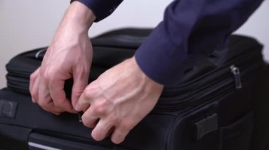 Siyah seyahat çantasında çift fermuar açan ve elbiselerini çıkaran bir erkeğin yakın çekim videosu. Seyahat ve bagaj konsepti. Seçici odak atışı