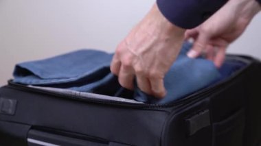 Bir adamın valizini toplamaya ve seyahat çantasının fermuarını kapatmaya hazırlanırken çekilmiş yakın çekim gösteri videosu. Seyahat ve bagaj konsepti. Seçici odak atışı