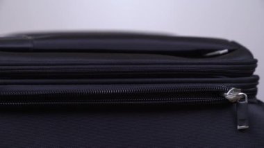 Siyah seyahat çantasının fermuarını kapatan bir adamın yakın çekimi. Yolculuk için bavul hazırlıyorum. İzole edilmiş, bulanık arkaplanda