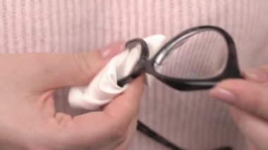 Gözlüklerinin lenslerini mikrofiber bir bezle temizleyen bir kadının ellerini kapatın. Oftalmoloji ve vizyon kavramı