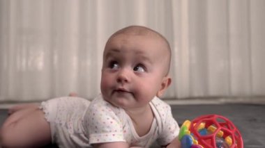Küçük bebek bebek bebek bebek odasında yerde, halının üstünde yatıyor. Kamera görüntüsüne yaklaşılıyor.