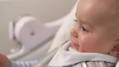 Sevgi dolu bir annenin, onu beslerken tatlı küçük oğlunun yüzünü silmesinin yan görüntüsü. Anne çocuğuna yemek veriyor. Boşluğu kopyala