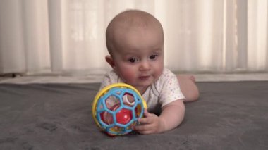 Evdeki yumuşak halıda renkli oyuncaklarla oynayan meraklı küçük bir çocuğun yakın plan portresi. Yeni dünyayı öğrenmenin ilk adımları. Çocuk emzirme kavramı