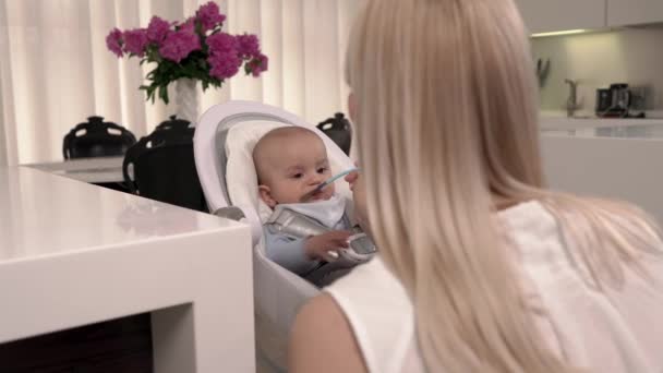 Cuidar Madre Alimentando Con Una Cuchara Pequeño Bebé Elegante Cocina — Vídeos de Stock