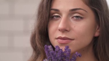 Güzel romantik bir kadının portresi. Elinde lavanta rengi bir buket tutarken ve çiçekleri koklarken. Seksi ve erotik atmosfer