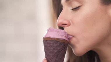 Dondurmanın tadını çıkaran baştan çıkarıcı genç bir kadın. Flört eden romantik kız. İzole edilmiş, bulanık arkaplanda, yakın çekim gösteri videosu