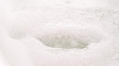 Sabunlu köpüklere ve kabarcıklara akan saf su akıntısı. İzole edilmiş