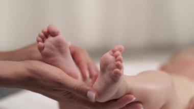 Sevgi dolu anne, yeni doğmuş bebeğini emzirirken minik bacaklarına hafifçe dokunuyor. Yakın plan. İzole edilmiş, bulanık arkaplanda