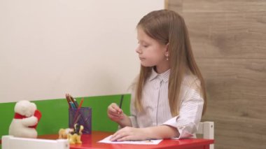 Klinikteki oyun odasında çizim yapan küçük tatlı bir kızın sağdan sola görüntüsü. Rahatlatıcı hasta. Pediatri ve sağlık konsepti