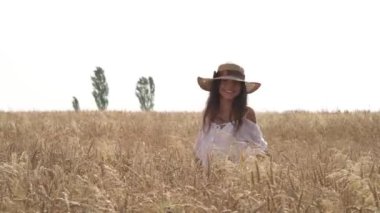 Hasır şapkalı çekici bir kadın güpegündüz tarlada yürüyor. Neşeli kız eğleniyor