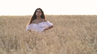 Gün batımında buğday tarlasında duran düşünceli genç kız..