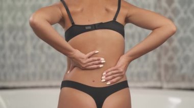 Kadın vücudu arka omurgasında ağrı gösteriyor. Bir kadın masaj hareketleriyle sırtına dokunuyor. Yakın plan, izole, bulanık arkaplan