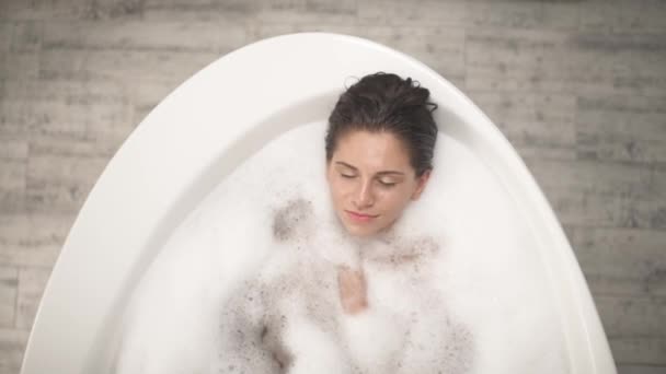 一个性感的年轻女子 一头长长的湿透了的黑发躺在浴缸里 她的照片尽收眼底 有诱惑力的女人在浴室情色概念 — 图库视频影像