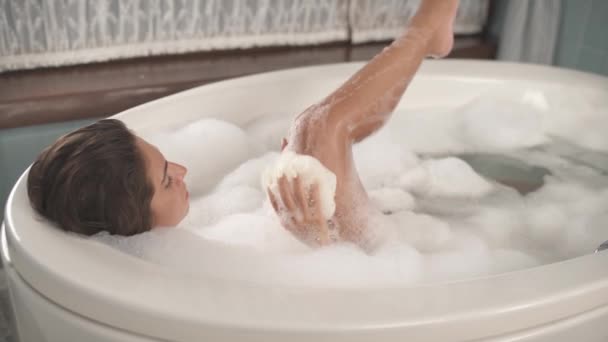 一个漂亮女人在泡泡浴的时候洗她的纤细腿的特写镜头 情欲的概念 选择性对焦射击 — 图库视频影像