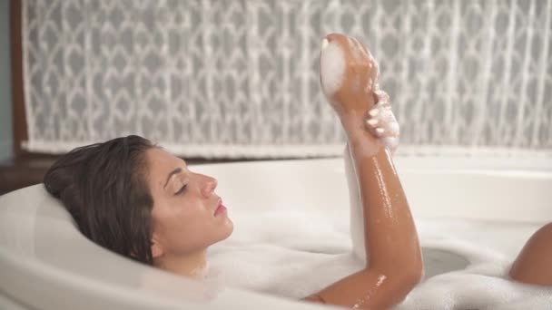 一个年轻的有诱惑力的女人一边摸着她的手部光滑的皮肤一边放松地洗澡的侧面视图 漂亮的女性身体 情色概念 — 图库视频影像