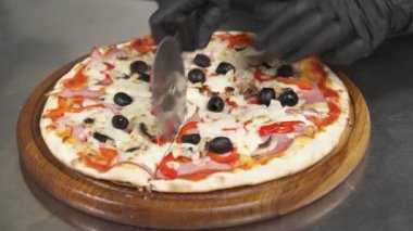 Profesyonel şef paten bıçağıyla birkaç dilim pizza keser. Tahta tahtada taze pişmiş lezzetli pizzanın yakın çekimi. Fast food konsepti