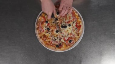 Profesyonel şefin havadan çekilmiş görüntüleri. Pizzayı tekerlekli bıçakla dilimliyor. Fast food konsepti