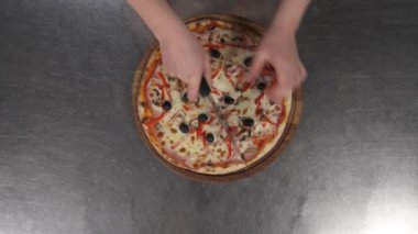 Profesyonel bir aşçının paten bıçağıyla pizzayı dilimleme görüntüsü. Tahta tahtada taze pişmiş lezzetli pizza. Fast food konsepti