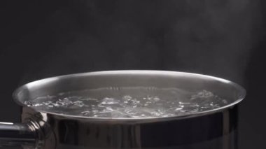 Tencerenin üstünde buhar var. İzole edilmiş, siyah arkaplanda