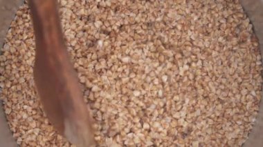Tahta kaşıkla karıştırılmış bir tencerede kaynamış karabuğday tohumları. Yemek pişirme konsepti