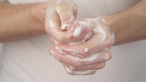 白いTシャツを着た白人男性の正面図は 石鹸と一緒にそれらをこすりつけることによって彼の手を泡立てる 手をこすり — ストック動画