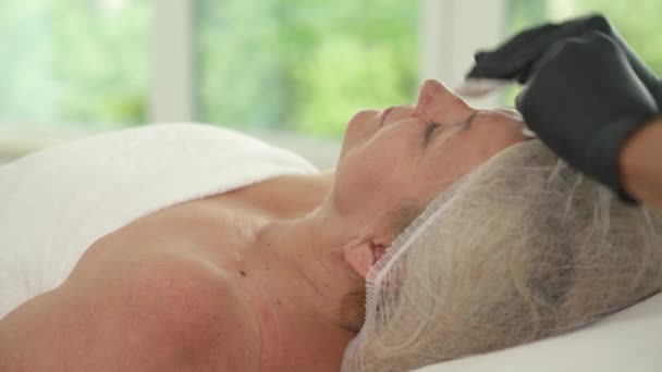 Kosmetolog Čistí Obličej Starší Ženy Houbami Pacient Ležící Gauči Zavřenýma — Stock video