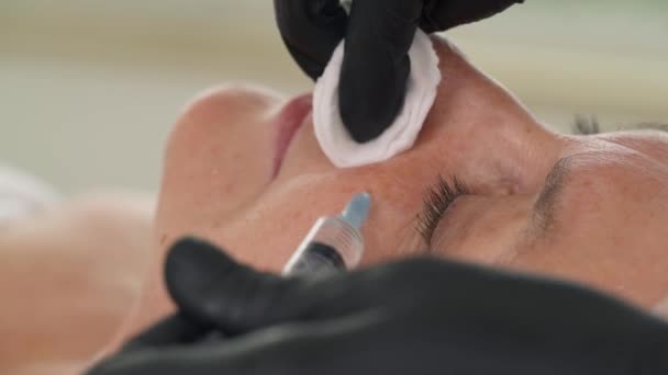 審美的な医療手順 アンチエイジング化粧品 高齢患者への複数の注射を行う専門家 頬への注射 — ストック動画