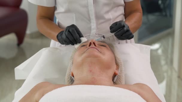 診療所で針療法 専門の美容師のフロントビューは 手順中に女性の額の皮膚に複数の注射を行います — ストック動画