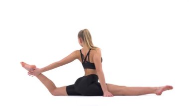 Siyah spor kıyafetli genç bir kadın uzun sicim pozisyonunda esneme egzersizi yapıyor. Spor konsepti