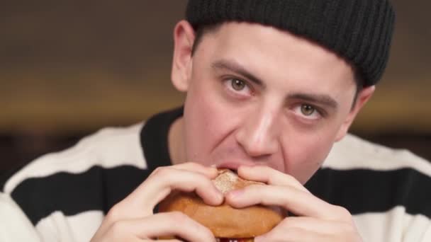迷人的黑发小伙子喜欢在快餐店吃新鲜熟食汉堡 一个面食肮脏的男人的特写镜头 城市食品概念 — 图库视频影像