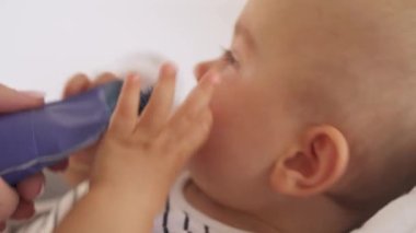 Ağlayan çocuğuna meyve püresi veren şefkatli bir annenin yakın plan görüntüsü. Çocuk bakıcılığı. Seçici odak