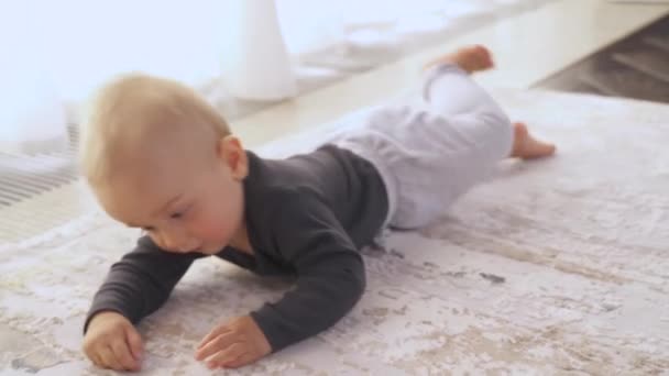 一个可爱的小宝宝的特写爬到地板上 快乐的蹒跚学步的男孩对着相机笑 快乐的童年 — 图库视频影像
