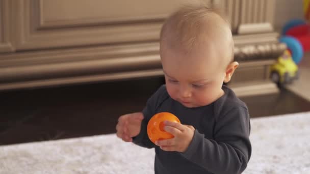 Close Menino Pequeno Curioso Segurando Mastigando Pequeno Brinquedo Laranja Primeiros — Vídeo de Stock