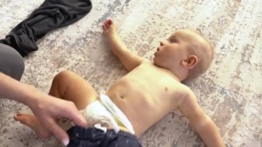 Küçük bebeğini giydiren bir annenin yakın çekimi. Sevgi dolu ve şefkatli bir anne. Mutlu aile kavramı