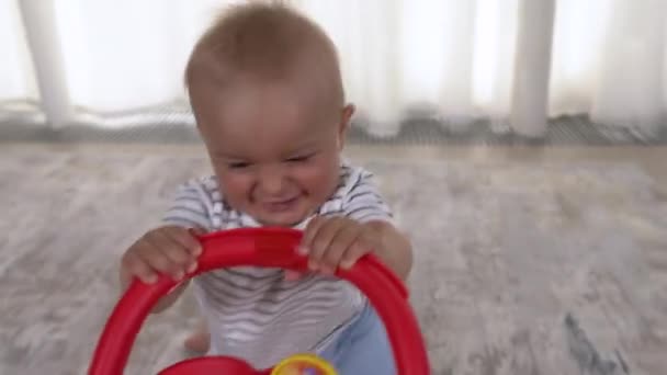 活泼的男婴带着一辆五颜六色的玩具推车爬到客厅里 快乐的童年护理儿童概念 — 图库视频影像