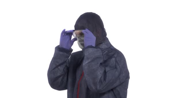 身穿防护服戴口罩的人把眼镜戴上 用大拇指举手表决摄像机 好的手签在白色背景下隔离的工作室拍摄 — 图库视频影像