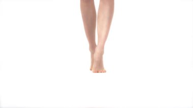 Çıplak ayaklı kadın bacaklarının kameraya doğru yürüdüğünü gösteren yakın çekim videosu. İzole edilmiş, beyaz arkaplanda