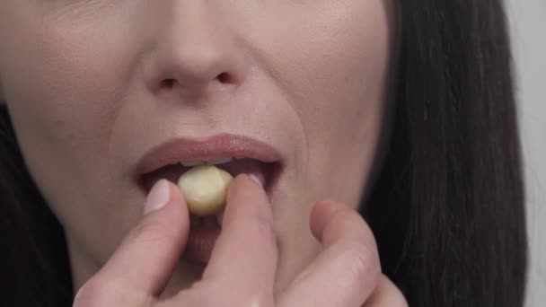 美しい女性の唇のクローズアップ 認知できない女がヘーゼルナッツを口の中に入れる — ストック動画