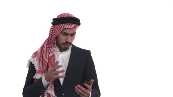 手里拿着智能手机的阿拉伯男人 看着屏幕 流露出惊讶的情绪 震惊的人使用他的小玩意 在白色背景下孤立无援 — 图库视频影像