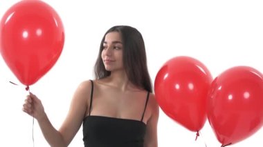 Kameraya gülümseyen, elinde kırmızı balonlarla çekici bir genç kadın. Sevgililer Günü ya da doğum günü konsepti