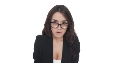 Gözlüklü genç beyaz kadın, hoşnutsuz bir bakışla kameraya bakıyor. El sallıyor ve başını sallıyor. Beyaz arkaplanda izole