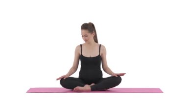 Doğum öncesi yoga. Kafkasyalı hamile kadın bacak bacak üstüne atmış bir şekilde mindere oturuyor. Beyaz arkaplanda izole.