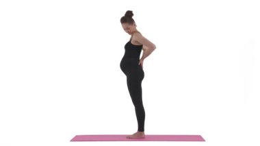Beyaz hamile bir kadının yoga minderinde durup sırtına masaj yapması. Annelik konsepti. Beyaz arkaplanda izole