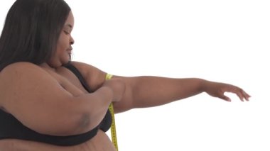 Aşırı kilolu, beyaz arka planda izole edilmiş üst kolunu ölçen Afrikalı Amerikalı kadının yakın çekimi.