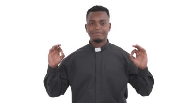 Yakışıklı Afrikalı rahibin portresi başparmak ve işaret parmağını daire şeklinde bağlıyor ve iki elini de beyaz arka planda izole edip işaret dilini düz tutuyor.