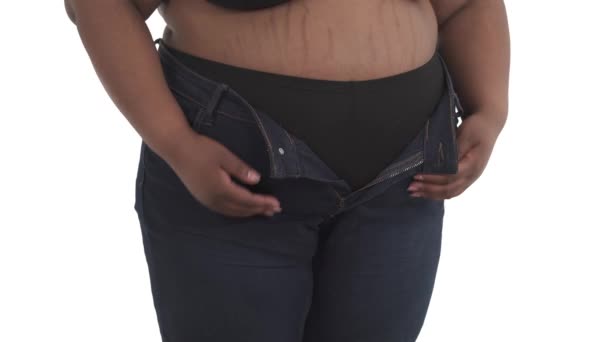 无法辨认的黑色加尺寸女性身体的特写不能把牛仔裤系在与白色背景隔离的腰部 — 图库视频影像